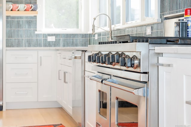 kitchen view of tasteful backsplash, white cabinetry, and light wood-style floors