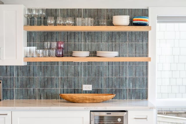 kitchen view of wine cooler, backsplash, and white cabinets