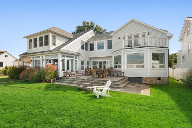 rear view of house with a balcony, a yard, a shingled roof, and a patio