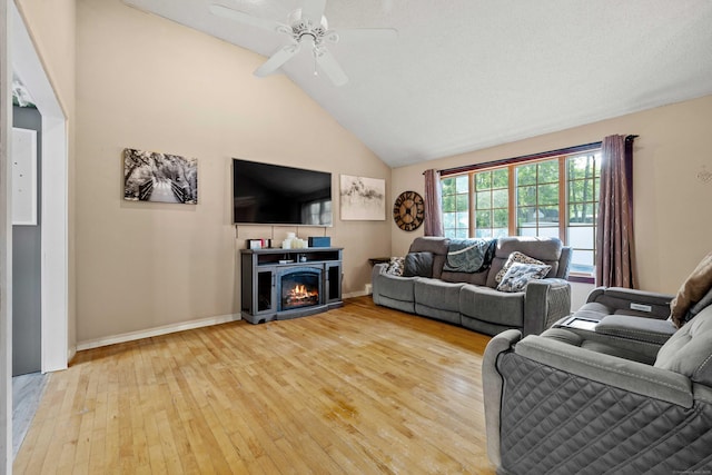 11 Osprey Ln, East Lyme, CT 06357 - living room with hardwood / wood-style floors, ceiling fan, high vaulted ceiling, baseboards, and a warm lit fireplace