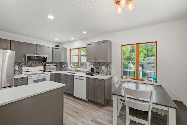 11 Osprey Ln, East Lyme, CT 06357 - kitchen with appliances with stainless steel finishes, gray cabinetry, a sink, tasteful backsplash, and light countertops