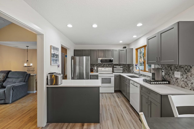 11 Osprey Ln, East Lyme, CT 06357 - kitchen featuring appliances with stainless steel finishes, gray cabinets, a sink, light wood-style flooring, and tasteful backsplash