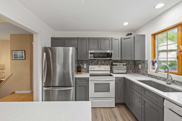 11 Osprey Ln, East Lyme, CT 06357 - kitchen featuring stainless steel appliances, a sink, gray cabinetry, light countertops, and backsplash