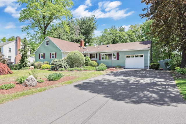 view of front of house with asphalt driveway, a garage, and a front yard