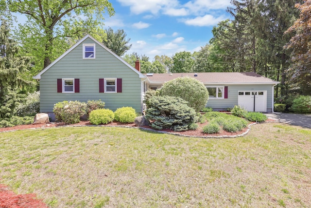 view of front of house featuring an attached garage, a chimney, a front yard, and asphalt driveway