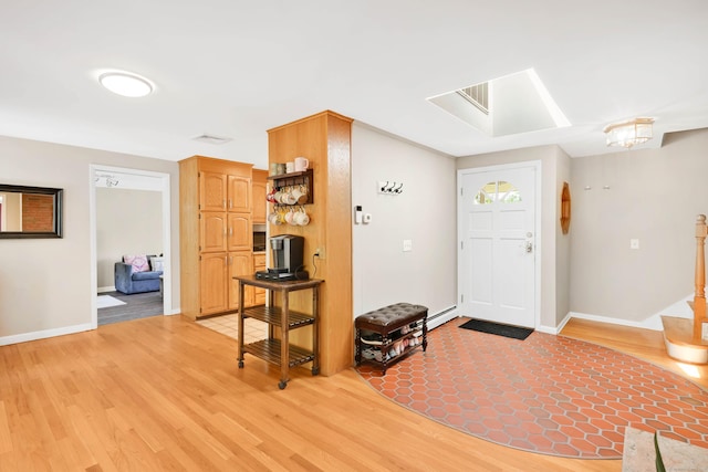 foyer entrance featuring light wood-style floors, a skylight, and baseboards