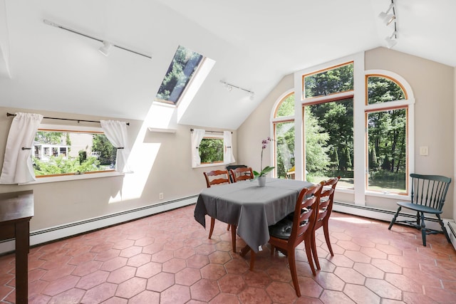 tiled dining space with track lighting, lofted ceiling, baseboard heating, and a skylight