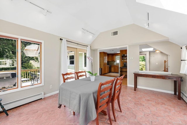 dining space featuring rail lighting, vaulted ceiling, a baseboard heating unit, and baseboards