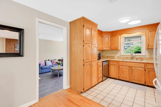 kitchen featuring a sink, dishwasher, light wood-style floors, and baseboards
