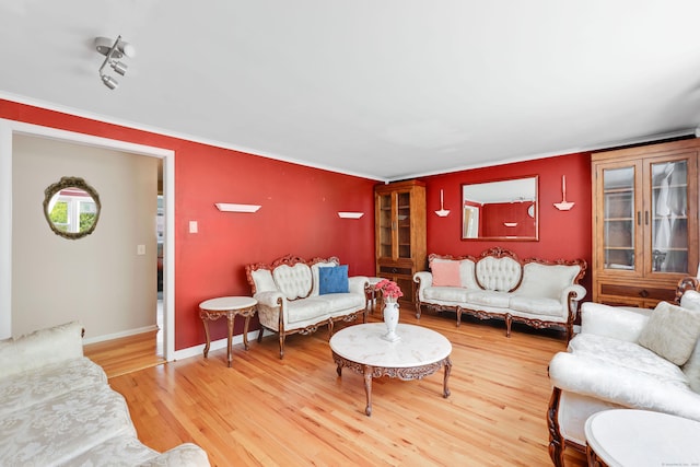 living room featuring wood finished floors, ornamental molding, and baseboards