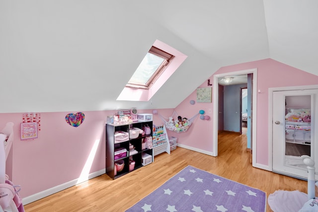 rec room featuring lofted ceiling, wood finished floors, baseboards, and a skylight