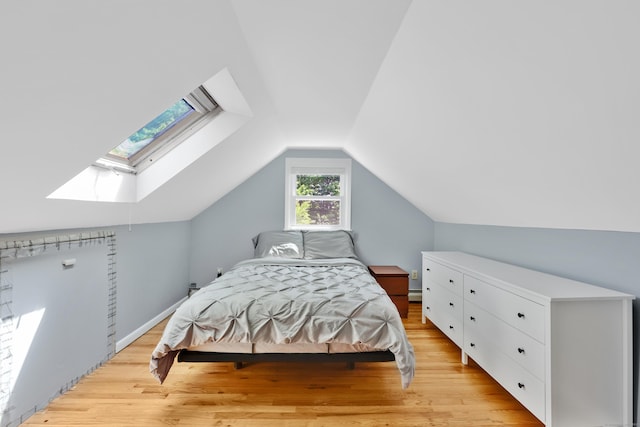 bedroom with a skylight, light wood-type flooring, vaulted ceiling, and baseboard heating