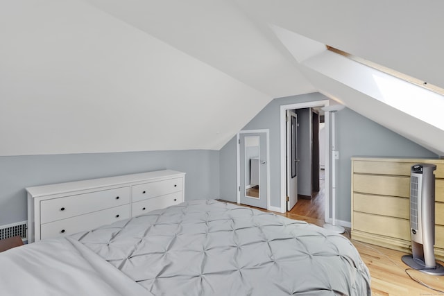 bedroom with light wood-style flooring, lofted ceiling, and a skylight