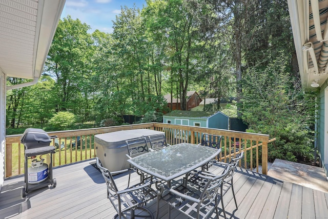 wooden terrace featuring outdoor dining space, a storage unit, area for grilling, and an outdoor structure