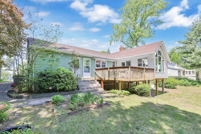 rear view of property with a wooden deck, a yard, and a chimney
