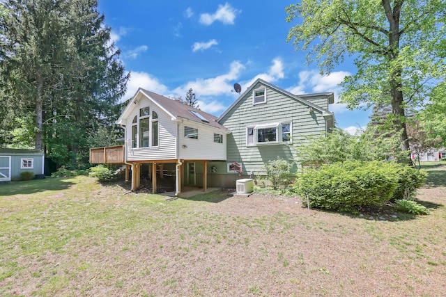 back of property featuring a wooden deck, a yard, an outbuilding, and a storage unit