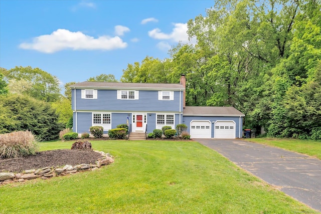 colonial house featuring a garage, driveway, a chimney, and a front lawn