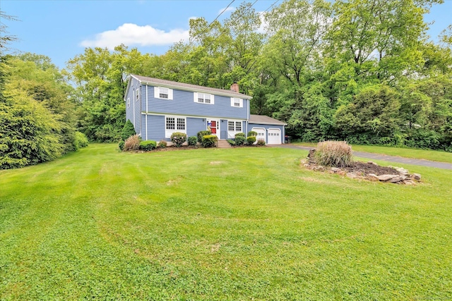 back of house with a chimney, a lawn, and a detached garage