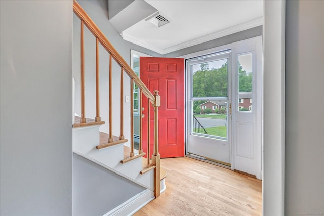 entrance foyer featuring crown molding, light wood finished floors, and stairs