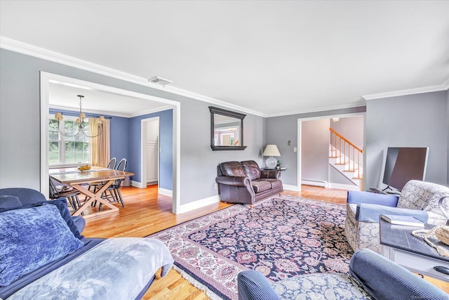 living room with wood finished floors, ornamental molding, stairway, baseboard heating, and baseboards