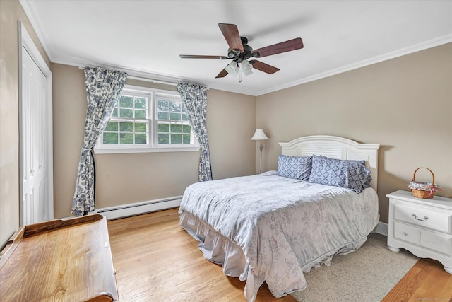 bedroom with baseboard heating, wood finished floors, crown molding, a ceiling fan, and a closet