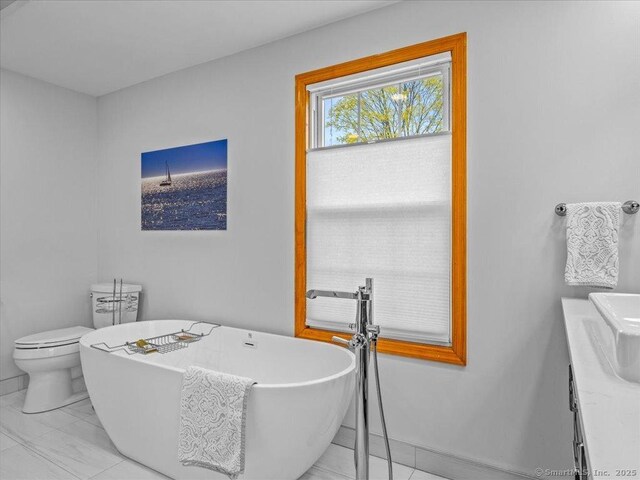 571 Pond Point Ave, Milford, CT 06460 - bathroom featuring a freestanding tub, toilet, vanity, and baseboards