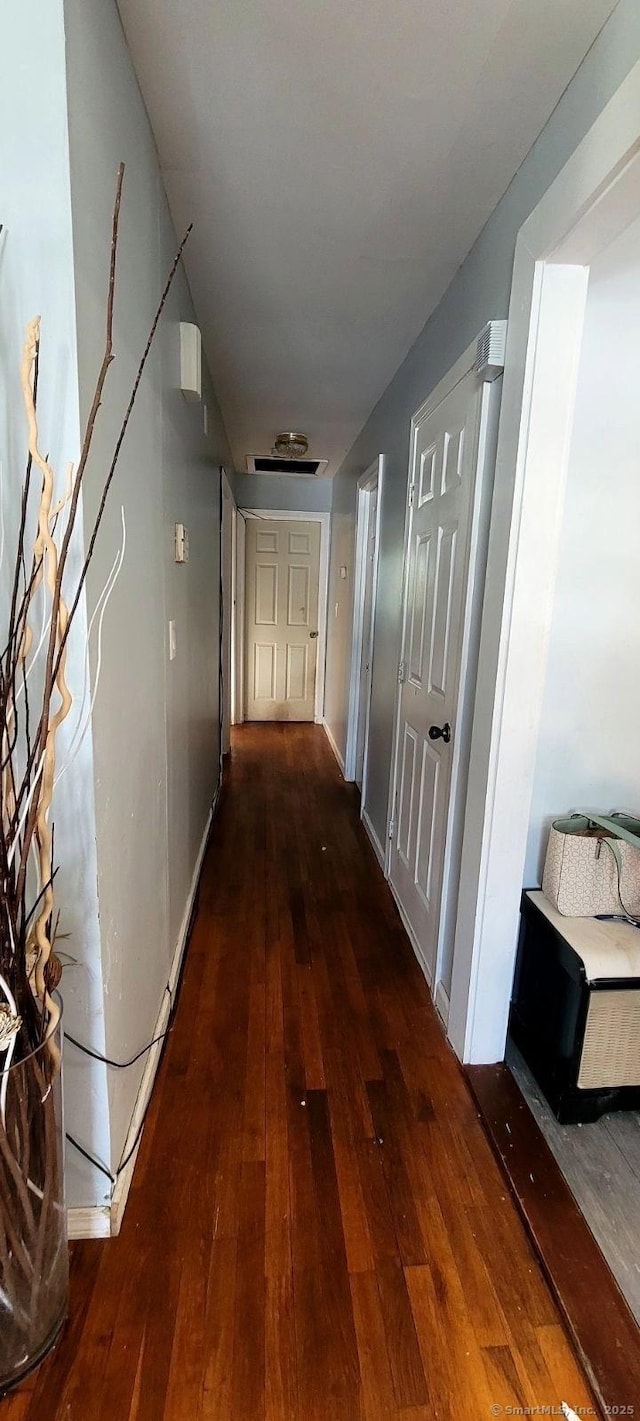 corridor with hardwood / wood-style floors and baseboards