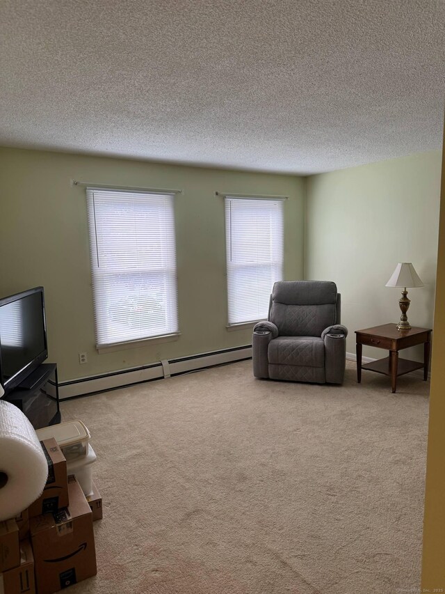 sitting room with a baseboard radiator, a textured ceiling, and carpet flooring