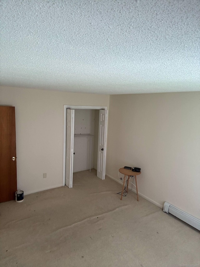 unfurnished bedroom with carpet, a closet, a textured ceiling, and a baseboard heating unit