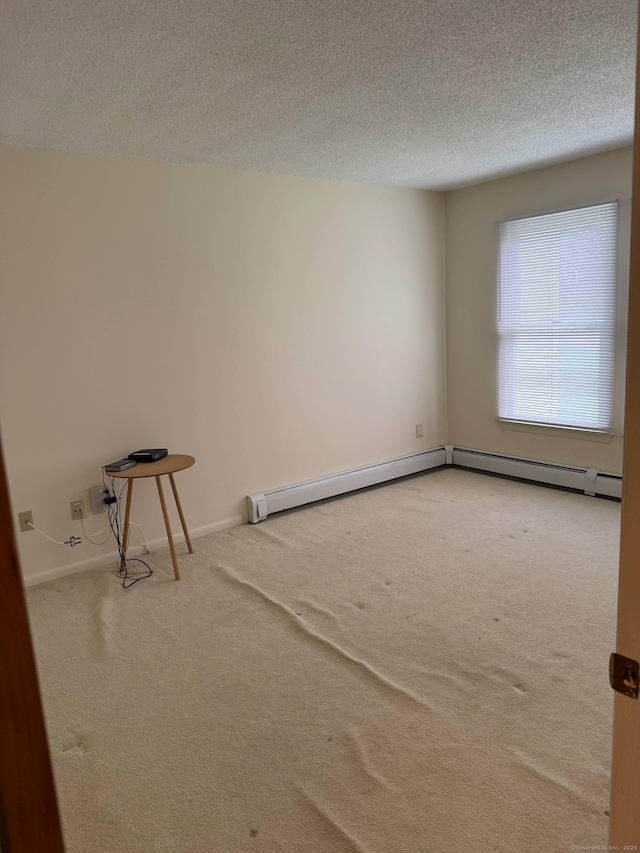 spare room featuring carpet floors, a textured ceiling, and baseboards