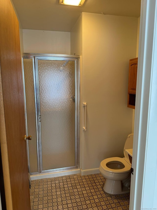 bathroom with a stall shower, baseboards, toilet, and tile patterned floors
