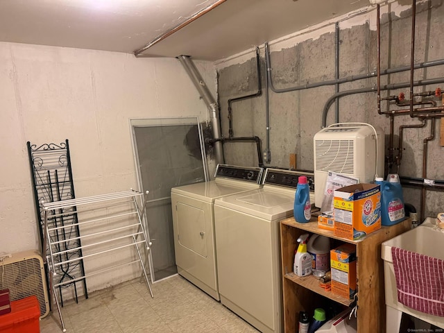 laundry area with washing machine and dryer, light floors, and a sink