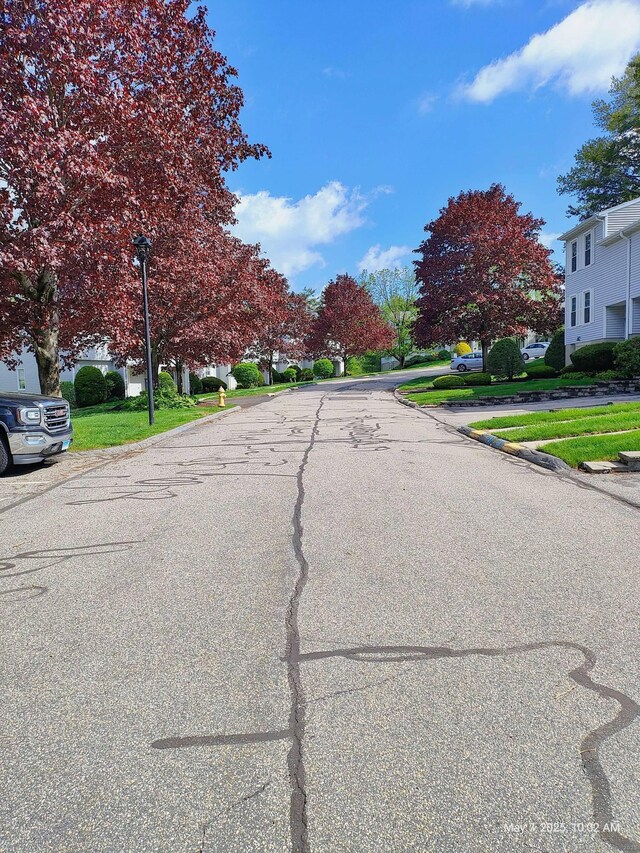 view of asphalt road with street lights, curbs, and a residential view