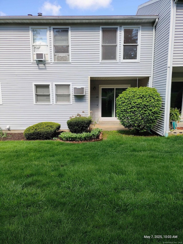 view of front of house featuring a front yard, cooling unit, and a wall mounted AC