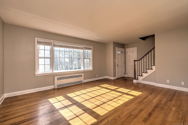 foyer entrance featuring radiator heating unit, wood-type flooring, baseboards, and stairway