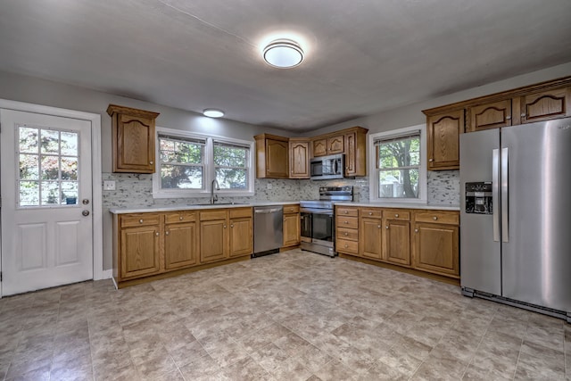 kitchen featuring stainless steel appliances, a sink, light countertops, and brown cabinets