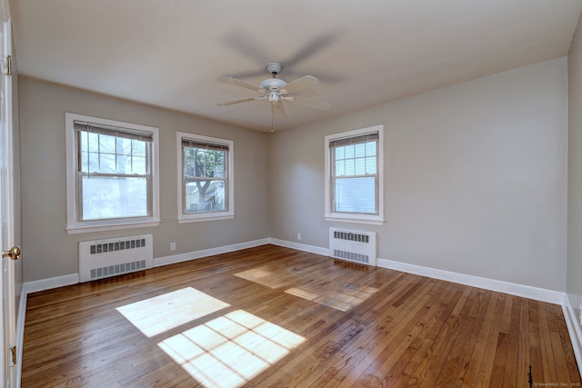 spare room featuring radiator heating unit, healthy amount of natural light, and hardwood / wood-style flooring