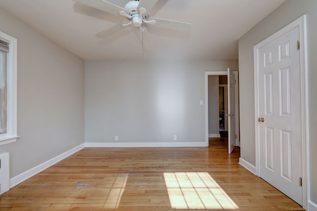 unfurnished room with light wood finished floors, a ceiling fan, and baseboards