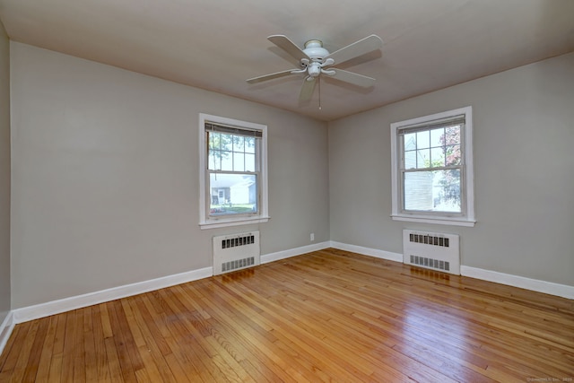 unfurnished room featuring radiator, healthy amount of natural light, and light wood-style floors