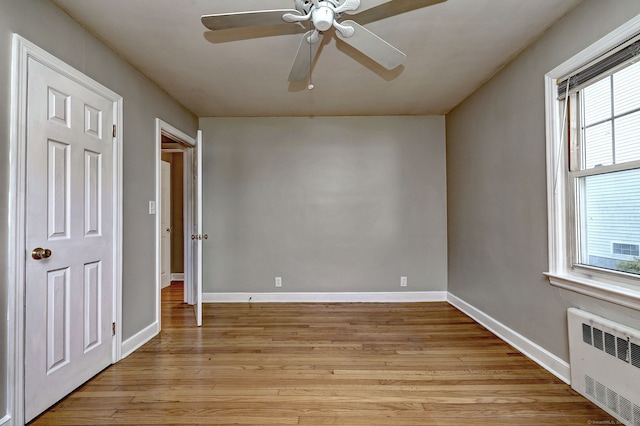 unfurnished bedroom with radiator, light wood-style floors, and baseboards