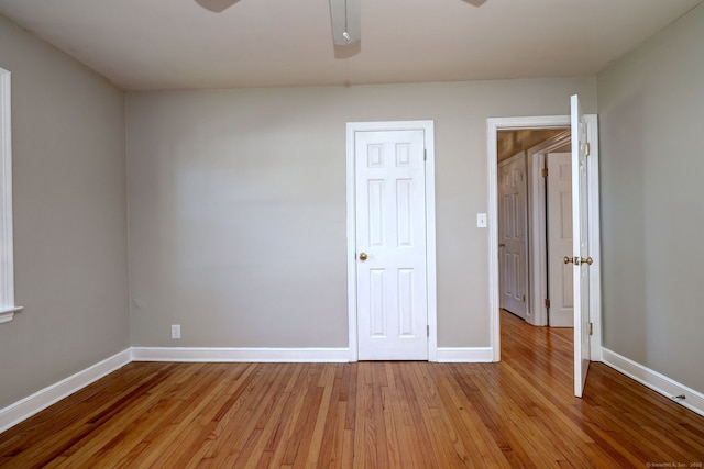 unfurnished room with ceiling fan, light wood-style floors, and baseboards