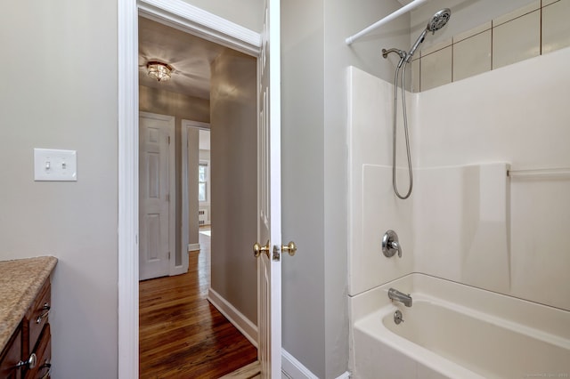 bathroom featuring baseboards, wood finished floors, vanity, and shower / bathtub combination