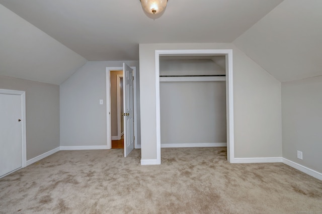 unfurnished bedroom featuring lofted ceiling, carpet flooring, a closet, and baseboards