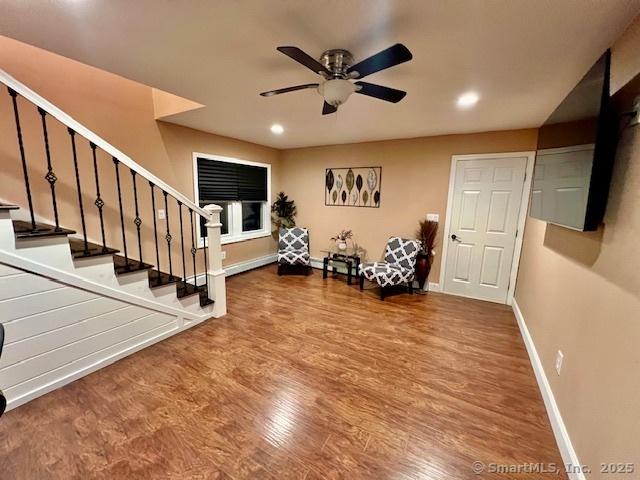 living area featuring baseboards, stairs, wood finished floors, a ceiling fan, and recessed lighting