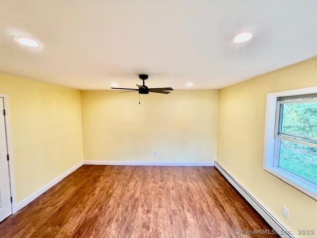 spare room with a baseboard heating unit, wood finished floors, a ceiling fan, recessed lighting, and baseboards