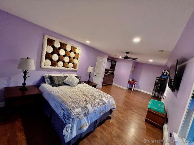 bedroom featuring wood finished floors, recessed lighting, baseboard heating, baseboards, and a ceiling fan