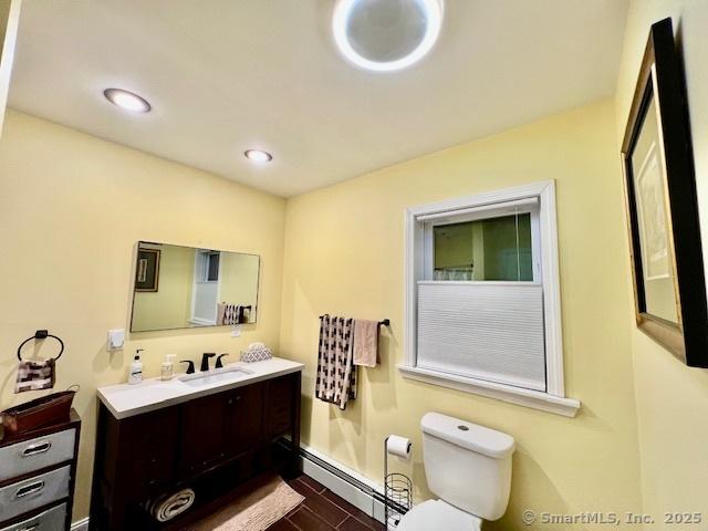 bathroom featuring a baseboard radiator, toilet, vanity, and baseboards