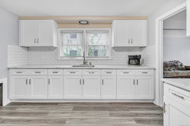 592 Courtland Ave, Bridgeport, CT 06605 - kitchen with a sink, white cabinetry, backsplash, and light wood-style floors