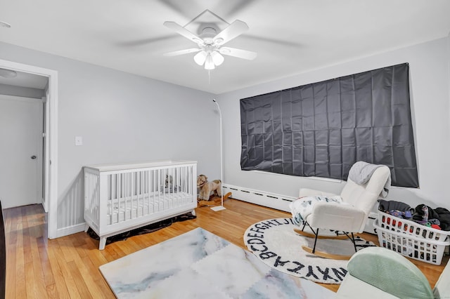 592 Courtland Ave, Bridgeport, CT 06605 - bedroom with baseboard heating, wood finished floors, a ceiling fan, and a baseboard heating unit