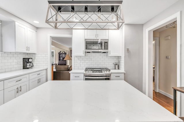 592 Courtland Ave, Bridgeport, CT 06605 - kitchen with appliances with stainless steel finishes, white cabinetry, backsplash, light stone counters, and recessed lighting